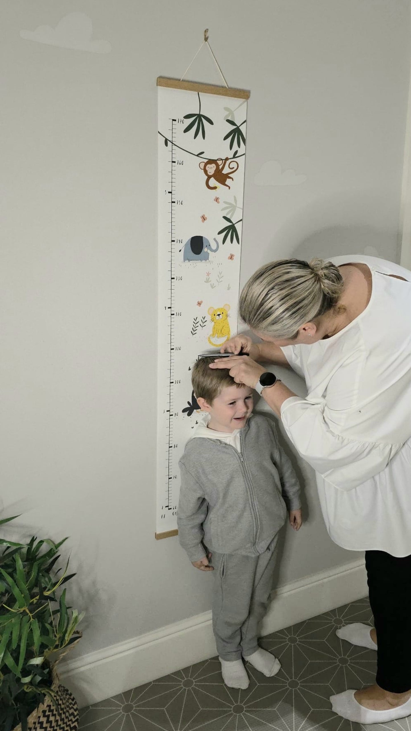 mum measuring child and recording height on canvas height chart
