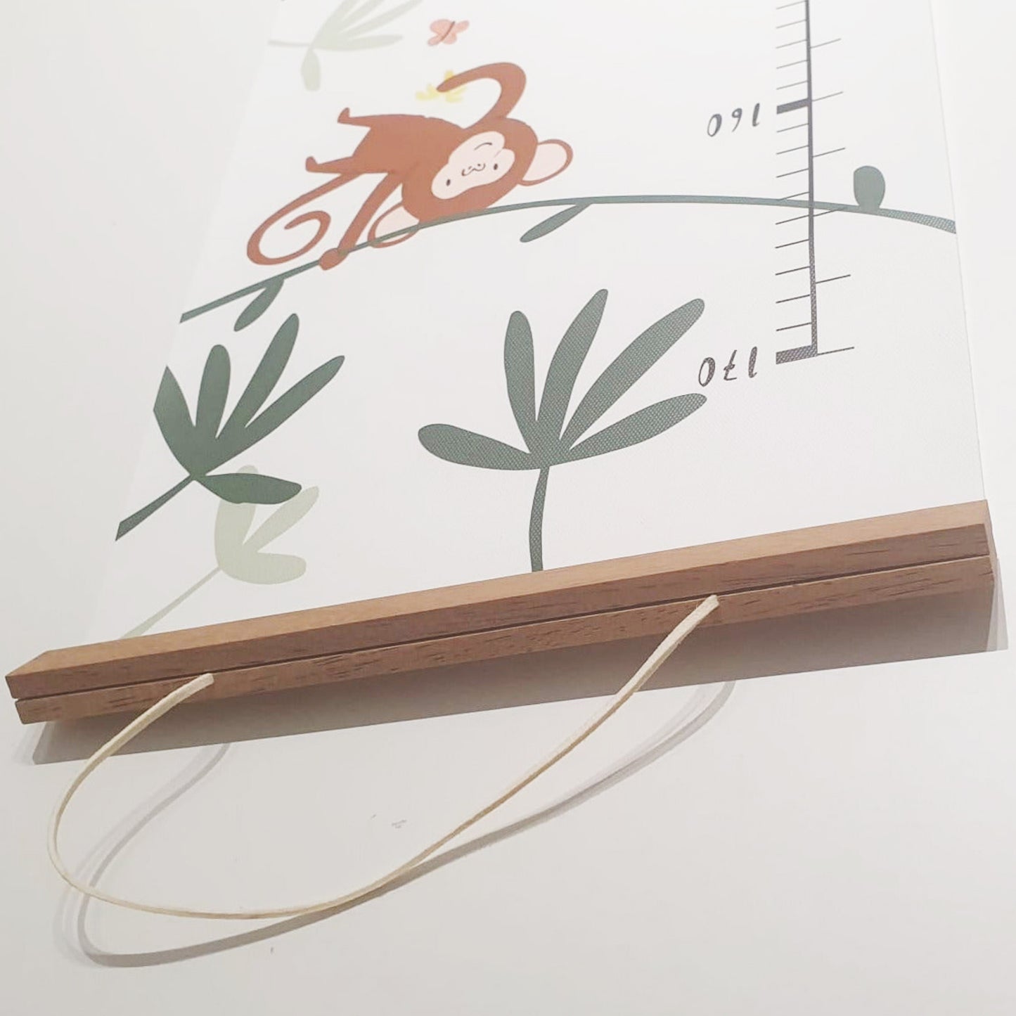 Canvas jungle height chart hanging on wall with wooden frame and included wall hook