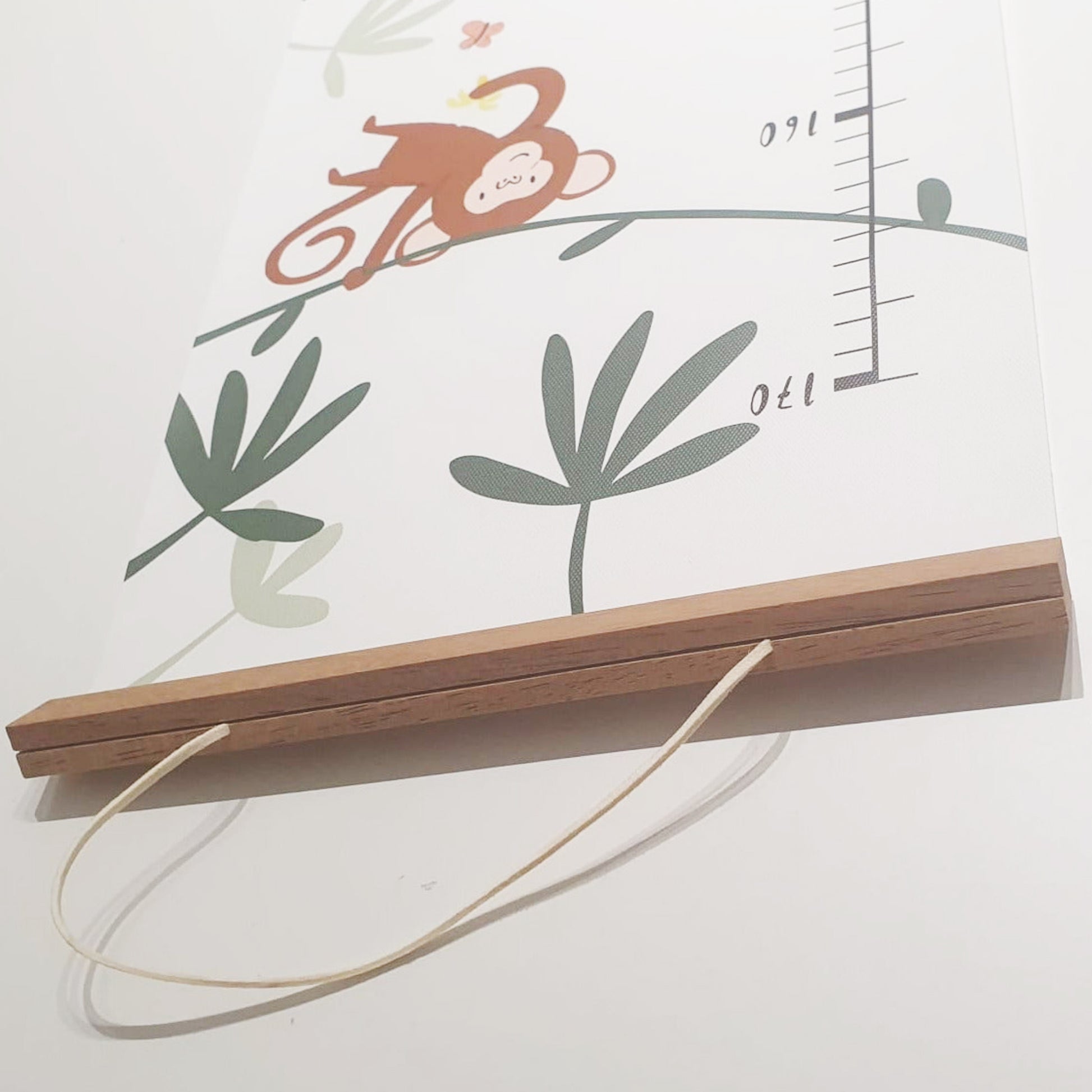 Canvas jungle height chart hanging on wall with wooden frame and included wall hook