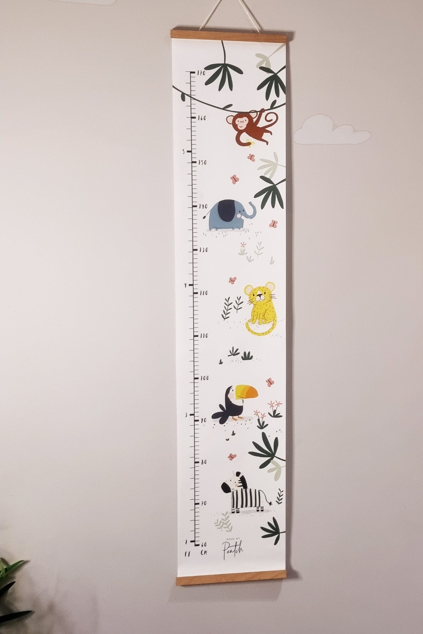 Canvas jungle height chart hanging on wall with wooden frame and included wall hook