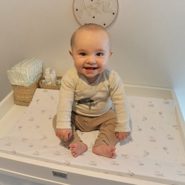 Baby sitting on baby changing mat, baby changing pad with a safari animal print