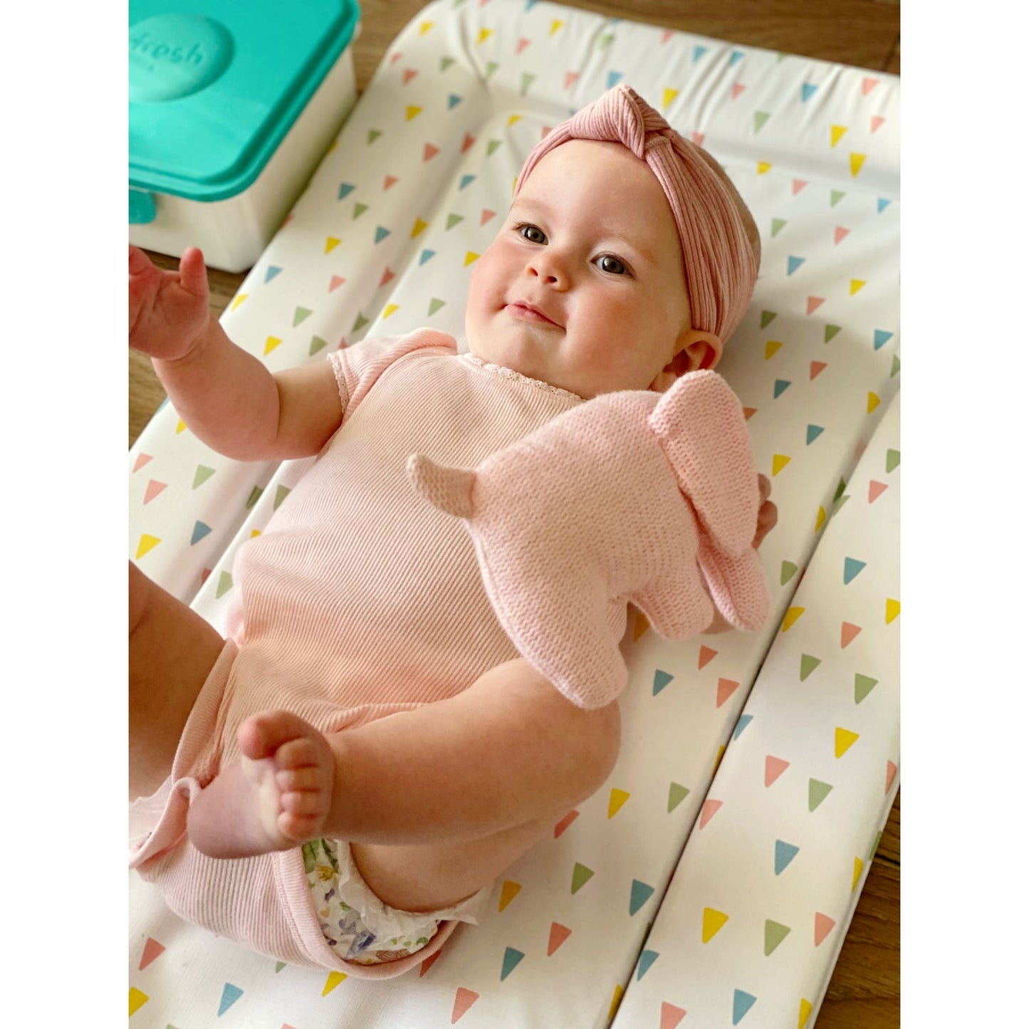 baby changing mat with baby girl holding a pink elephant in nursery